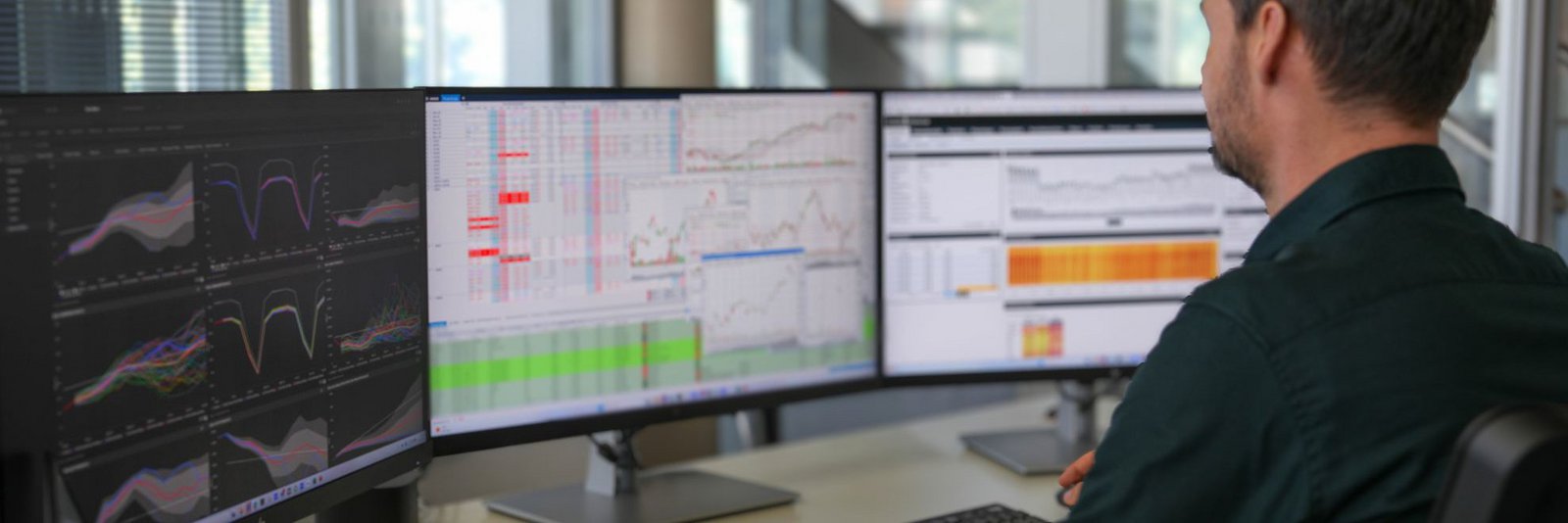 Energielogitik für Stadtwerke - ein Mann sitzt vor zwei Bildschirmen und anallysiert Graphen