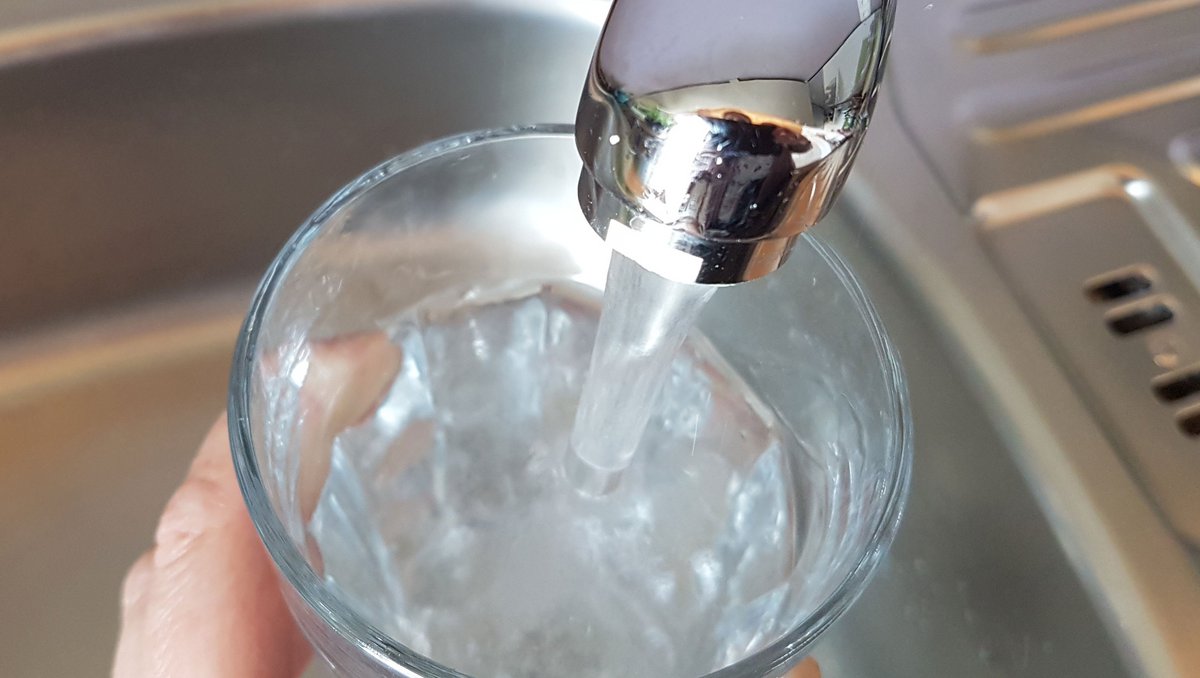 Glas wird mit Trinkwasser gefüllt