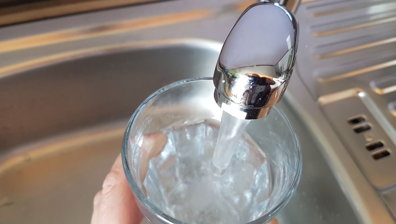 Glas wird mit Trinkwasser gefüllt